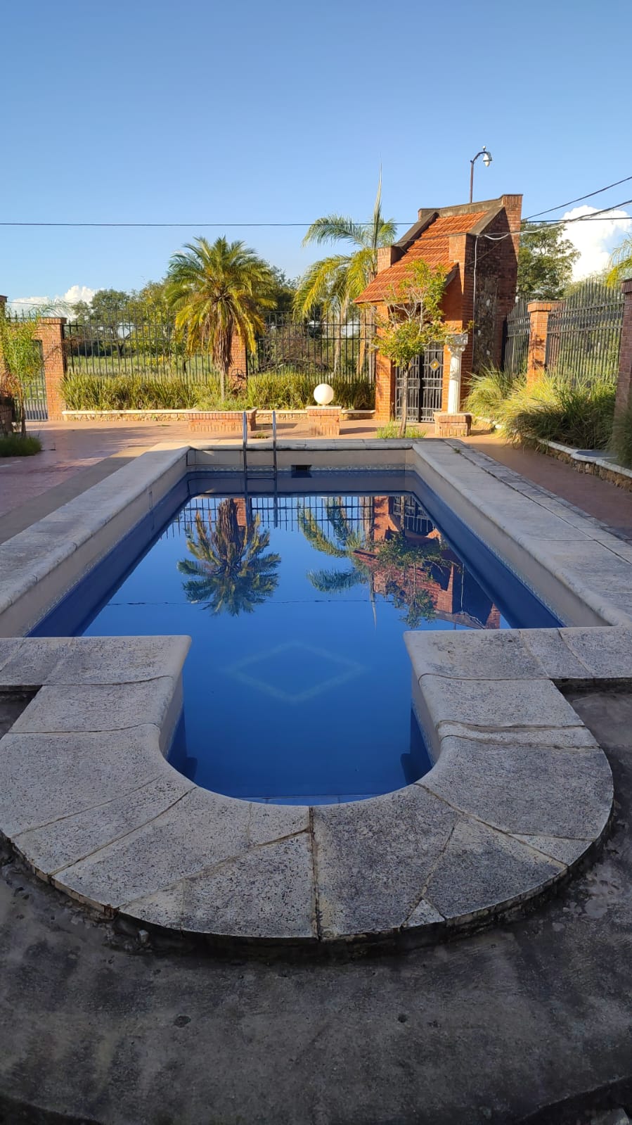 Piscina iluminada y reposeras en Del Pomar Hotel Boutique